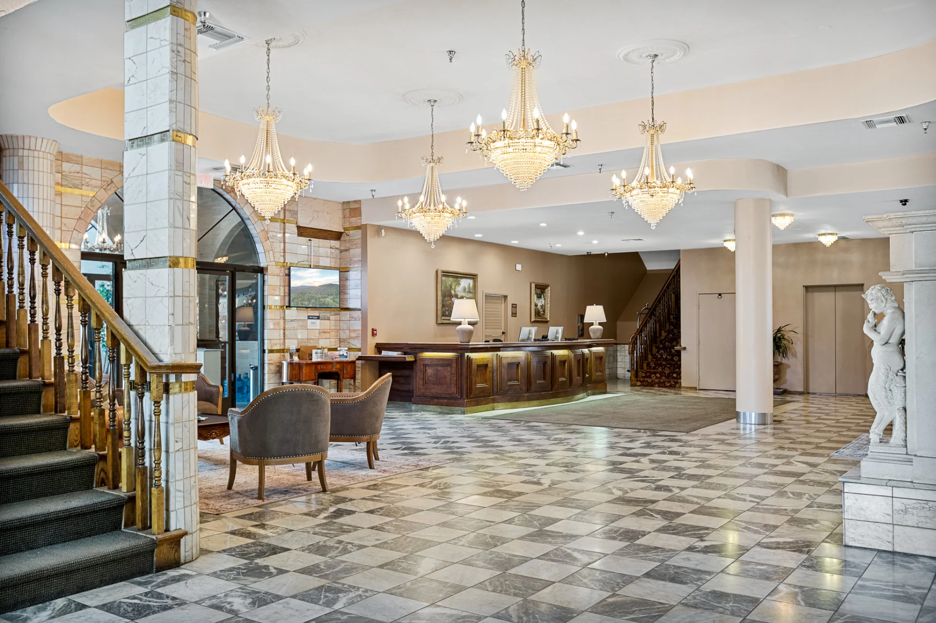 lobby checkered floor, chandeliers, check-in desk, and grand staircase